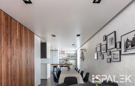 Esszimmer Moderner Essbereich mit langem Tisch, schwarzen Stühlen, Fotowand, Holzpaneelen, weißer Spanndecke und stilvoller Bar.