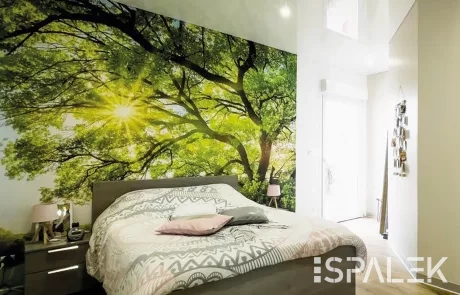 Schlafzimmer2 Helles Schlafzimmer mit Spanndecke, großem Wandbild eines sonnenbeschienenen Baums, Doppelbett, Nachttischen und Holzboden.