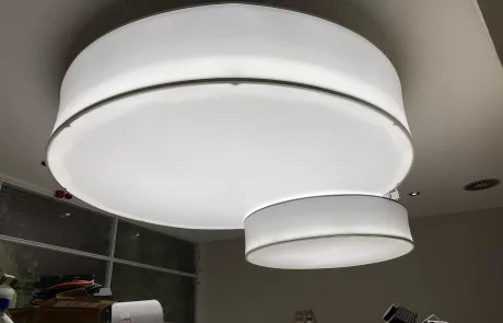 Zwei große, moderne runde Deckenleuchten mit weißen Diffusoren hängen an einer weißen Decke im Museum Sensoria Holzminden.