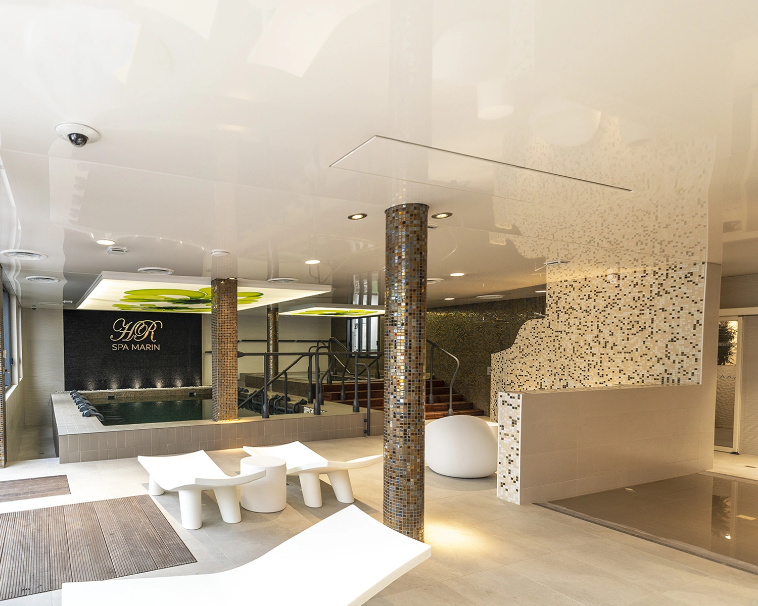 Modernes Spa mit Mosaikfliesen, Liegestühlen, Whirlpool und stimmungsvoller Beleuchtung; HR SPA MARIN Logo an der Wand.