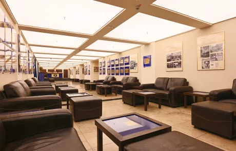 Lichtburg Geräumige, moderne Lounge in der Lichtburg Essen mit schwarzen Ledersofas, niedrigen Tischen und Fliesenboden unter Einbaubeleuchtung.
