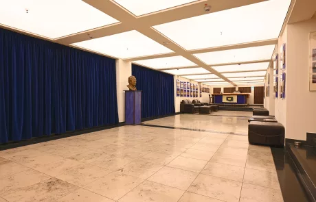 Lichtburg5 Großzügige, moderne Lobby in Essen mit beigem Fliesenboden, blauen Vorhängen, Sitzgelegenheiten und Empfangstresen.