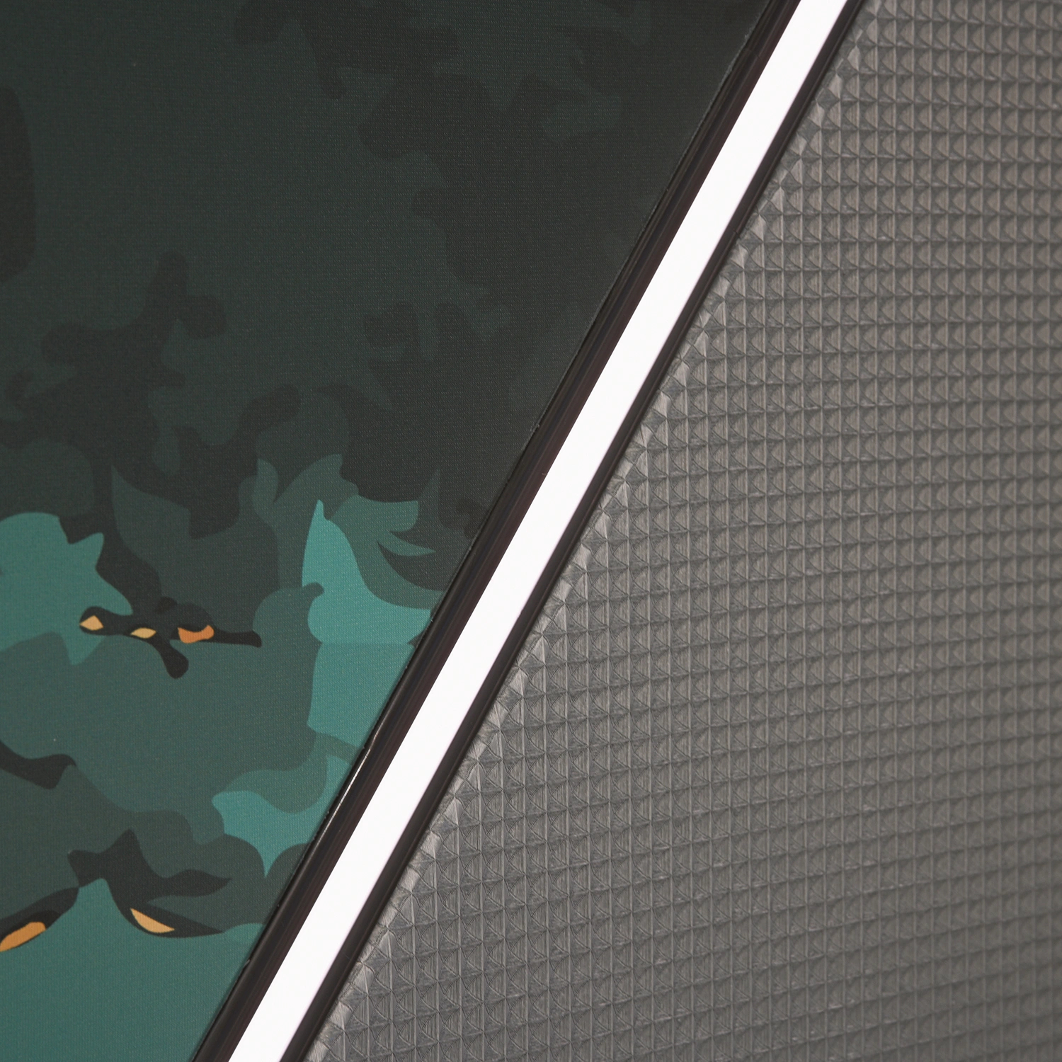 Wandbespannung-Detail Detailansicht zweier sich kreuzender Flächen: grün-schwarze Camouflage-Wandbespannung und strukturierte Oberfläche mit weißen Linien.