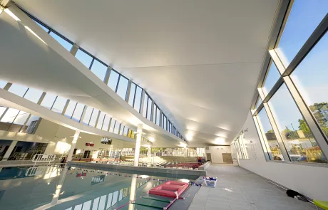 HD-9184-R Modernes Hallenbad im Centre Aquatique de Viroflay mit großflächigen Fenstern, schräger Decke und klar strukturierten Schwimmbahnen.