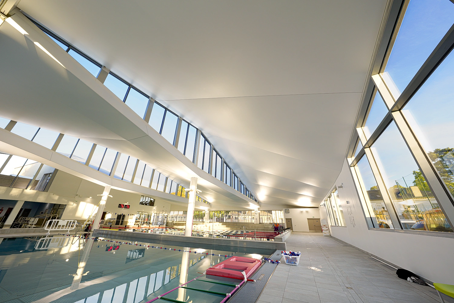 HD-9184-R Modernes Hallenbad im Centre Aquatique de Viroflay mit großflächigen Fenstern, schräger Decke und klar strukturierten Schwimmbahnen.