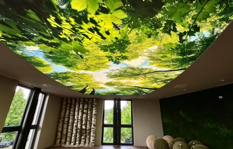 Moderner Besprechungsraum mit großen Fenstern, Holzboden und naturnaher Dekoration. Die Decke zeigt grünes Blätterdach.
