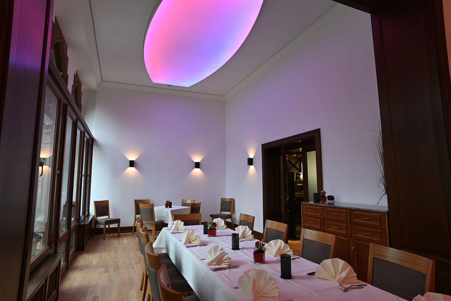 IMG_1388 Elegantes Esszimmer in Hirschburg mit langem Tisch, Holzstühlen, gedeckt und moderner Deckenleuchte in Rosa und Violett.