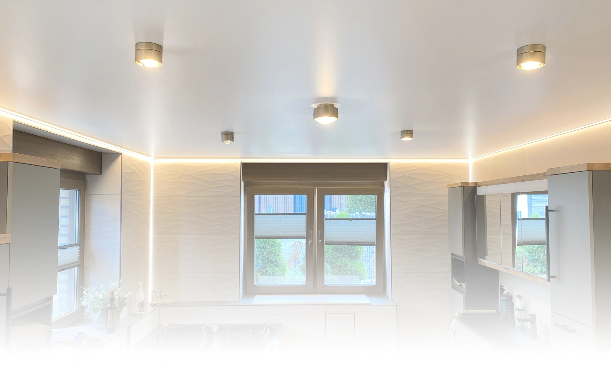 Moderne Küche mit grauen Schränken, Unterbauleuchten, innovativen Lichtlösungen, großem Fenster mit Jalousien und Topfpflanzen.