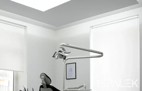PONGS-WCP-0097 Moderner Behandlungsraum mit schwarz-weißem Behandlungsstuhl, OP-Licht, Instrumenten und großen Fenstern mit weißen Jalousien.