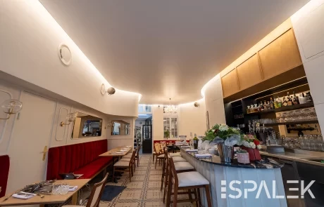 Modernes Restaurantinterieur in der Brasserie Dufour mit roten Polsterbänken, holzigen, gemustertem Fliesenboden und beleuchtetem Barbereich.