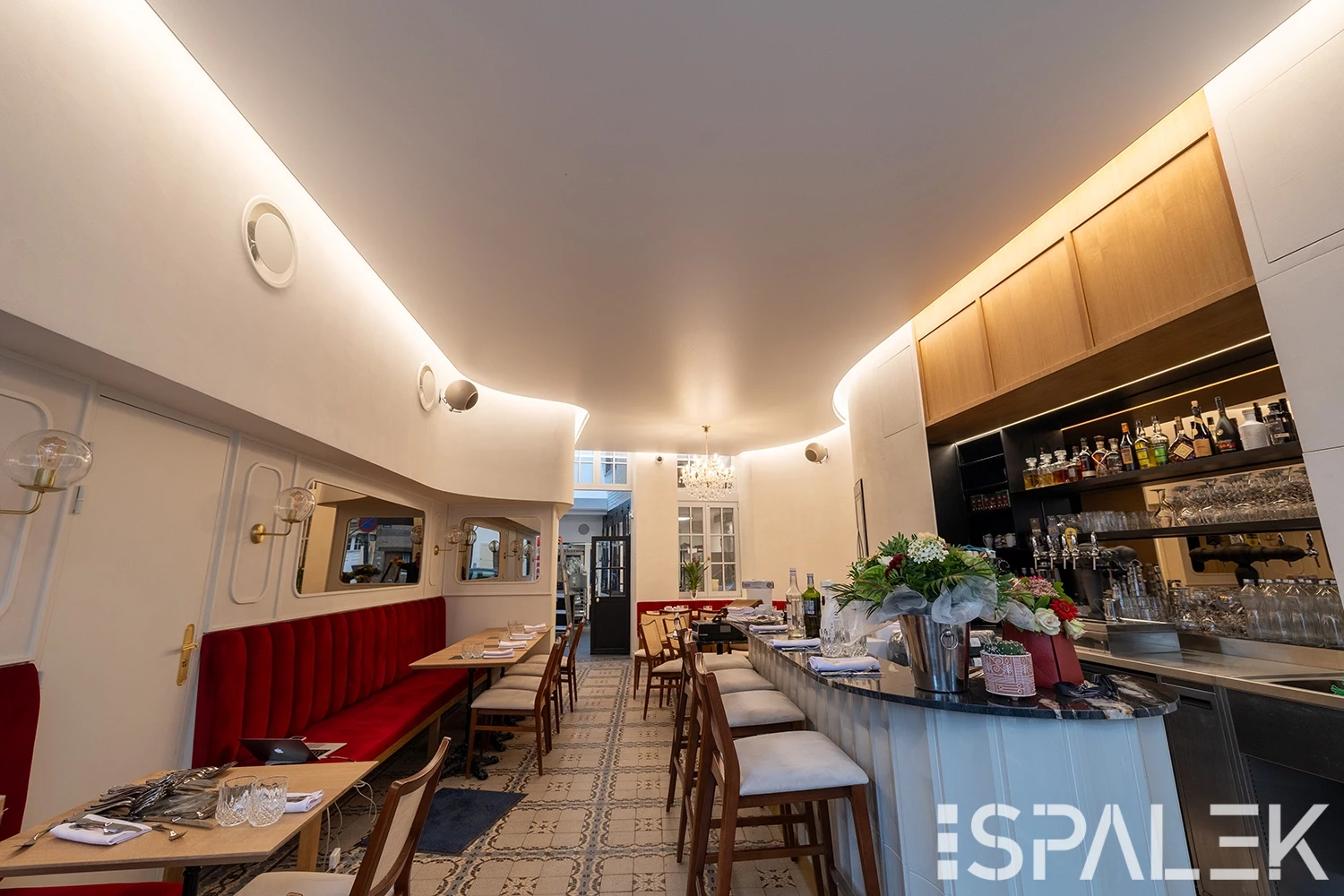 Modernes Restaurantinterieur in der Brasserie Dufour mit roten Polsterbänken, holzigen, gemustertem Fliesenboden und beleuchtetem Barbereich.